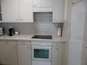 uma cozinha com armários brancos e um forno com placa de fogão em Apartment Blumenweg 2 by Interhome em Engelberg