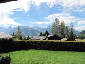a hedge in a yard with mountains in the background at Apartment Grüenbüelti by Interhome in Gstaad
