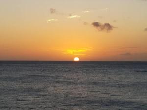 een zonsondergang over de oceaan met de zon in de horizon bij Breathtaking View - Playa Lagun - Curacao in Lagun