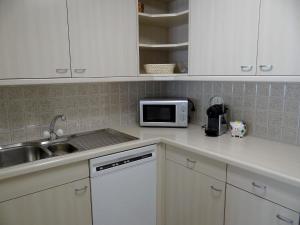 a kitchen with white cabinets and a sink and a microwave at Apartment Blumenweg 2 by Interhome in Engelberg