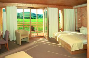 a bedroom with a bed and a view of a field at Natur & Wellnesshotel Breggers Schwanen - Bernau im Schwarzwald in Bernau im Schwarzwald +29 photos