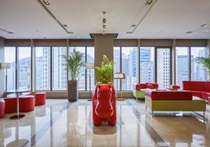 a large lobby with red furniture and large windows at Ibis Ambassador Myeongdong in Seoul