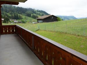 a balcony with a view of a field and a barn at Apartment Anne - Hochparterre by Interhome in Gstaad