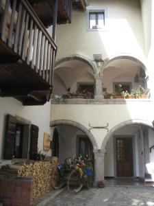 a building with arches and a balcony with flowers at Sot I Volz - locazione turistica in Arta Terme