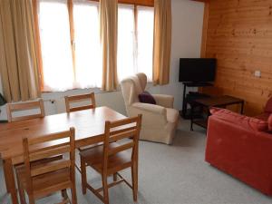 een woonkamer met een tafel en stoelen en een televisie bij Apartment Mireille Nr- 6 by Interhome in Gstaad
