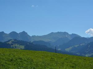 een groene heuvel met bergen op de achtergrond bij Apartment Mireille Nr- 3 by Interhome in Gstaad