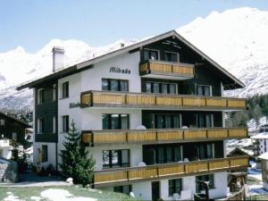 a large building with wooden balconies and snow covered mountains at Apartment Mikado by Interhome in Saas-Fee