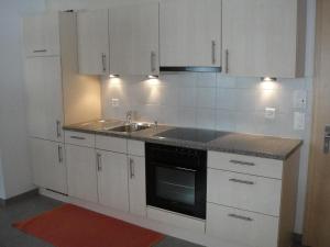 サースフェーにあるApartment Haus Alpenstern- Wohnung Distel by Interhomeの白いキャビネットとシンク付きのキッチン