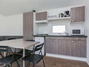 een keuken met een tafel en stoelen en een magnetron bij Holiday Home Hengelhoef-11 by Interhome in Aan de Wolfsberg