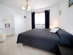 ein Schlafzimmer mit einem Bett mit einer schwarzen Decke und einem Fenster in der Unterkunft Holiday Home Amare Monte by Interhome in Benissa