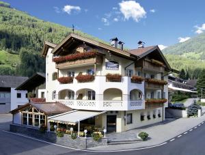 un gran edificio blanco con flores en los balcones en Hotel Garni Schneider, en Lutago