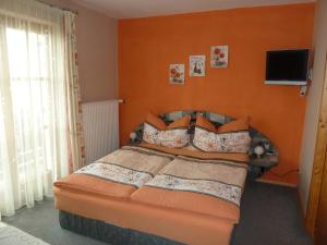 ein Schlafzimmer mit einem Bett mit einer orangefarbenen Wand in der Unterkunft Gästehaus Sonnenhang in Mondsee