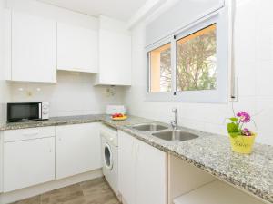 eine Küche mit weißen Schränken und einer Spüle und einem Fenster in der Unterkunft Apartment Velazquez-10 by Interhome in Roses + 19 Fotos