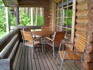 a wooden table and chairs on the porch of a cabin at Holiday Home 6309 by Interhome in Konginkangas