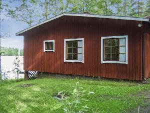 a small red house with two windows in the grass at Holiday Home 2235 by Interhome in Savonranta
