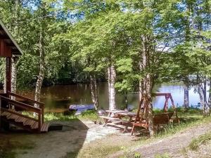 a picnic table next to a lake with trees at Holiday Home 2235 by Interhome in Savonranta