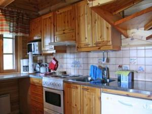 La cuisine est équipée de placards en bois et d'un four avec plaques de cuisson. dans l'établissement Holiday Home Korvenvalkama by Interhome, à Ahvionniemi