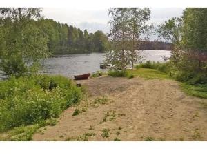 un camino de tierra junto a un lago con un barco en Holiday Home 5650 by Interhome, en Koskenpää