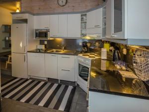 a kitchen with white cabinets and a black counter top at Holiday Home Koliwood a by Interhome in Kolinkylä