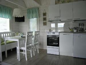 a kitchen with white appliances and a table and chairs at Holiday Home Mariantupa by Interhome in Muurame