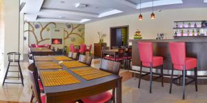 a restaurant with red chairs and tables and a bar at Hotel & Wellness Lesanka in Košická Belá