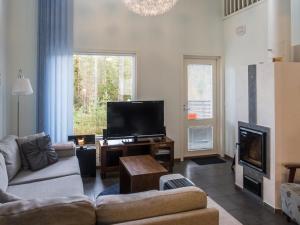 ein Wohnzimmer mit einem Sofa und einem Flachbild-TV in der Unterkunft Holiday Home Vuokatinlampi 7 b by Interhome in Lahdenperä