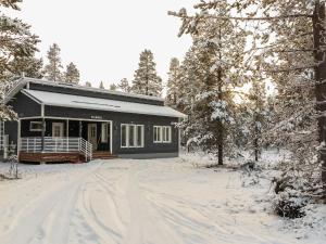 a black cabin in the snow with a dirt road at Holiday Home Kuukkeli by Interhome in Kyrö
