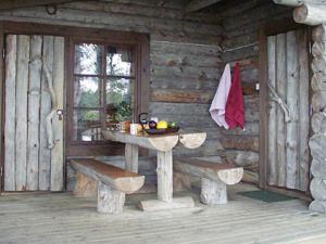 Cabaña de madera con mesa y bancos. en Holiday Home Kultaranta by Interhome, en Pätiälä