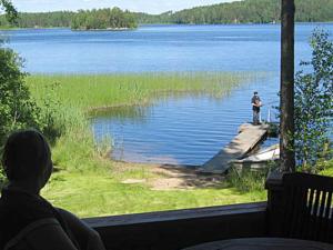 eine Person, die auf einer Veranda mit Blick auf einen See sitzt in der Unterkunft Holiday Home Pikkutupa by Interhome in Hyyrylä