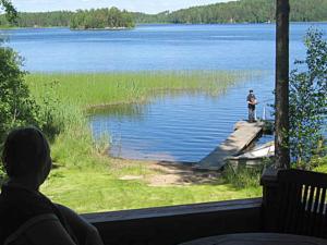 a person sitting on a porch looking out at a lake at Holiday Home Pikkutupa by Interhome in Hyyrylä