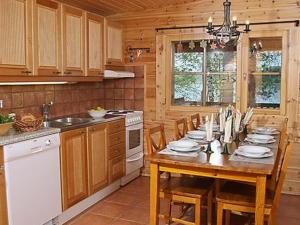 uma cozinha com uma mesa com cadeiras e um fogão em Holiday Home Divaanikivi by Interhome em Pätiälä
