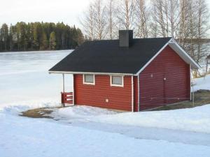 een rood huis met een zwart dak in de sneeuw bij Holiday Home Kallela by Interhome in Jokijärvi