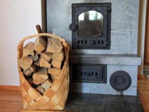a basket of wood next to a fireplace with a mirror at Holiday Home Pihlajatupa by Interhome in Kittilä