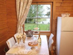 a dining room table with a refrigerator and a window at Holiday Home Alahuone by Interhome in Pätiälä