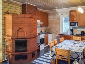 a kitchen with a brick fireplace and a table with chairs at Holiday Home Tervaleppä by Interhome in Torvoila