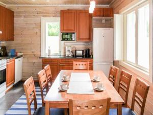 een keuken met een houten tafel met stoelen en een koelkast bij Holiday Home Tervaleppä by Interhome in Torvoila