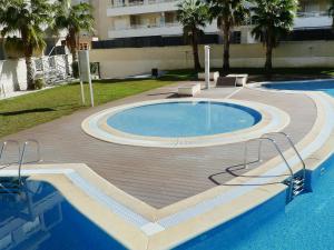a swimming pool with a wooden deck next to a building at Apartment Élegance by Interhome in Denia