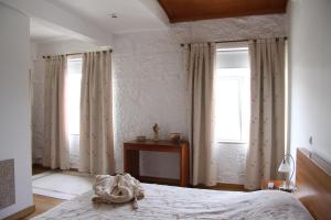 a bedroom with a bed and two windows at Casa da Quinta da Calçada in Cinfães
