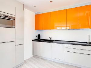 una cocina naranja y blanca con armarios blancos en Holiday Home Calatrava by Interhome, en Monte Pego