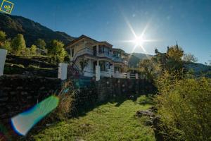 Una casa en una colina con el sol detrás. en Alt Life - Dharamkot (Mcleodganj), en McLeod Ganj