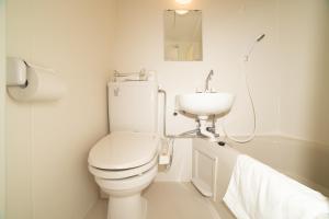 a white bathroom with a toilet and a sink at Tabata Oji Hotel in Tokyo
