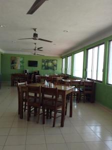 un restaurante con mesas y sillas de madera y ventanas en Hotel Villa de Pescadores, en Río Lagartos