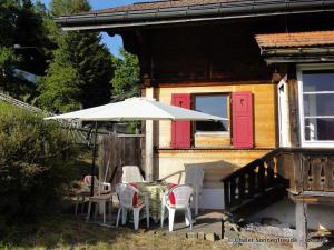 un patio con mesa, sillas y sombrilla en Apartment Sonnenfreude- Chalet by Interhome, en Schönried