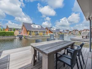 een houten tafel en stoelen op een terras met water bij Holiday Home De Meerparel-7 in Uitgeest