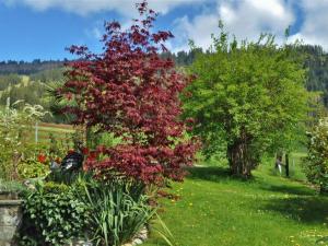a tree with red leaves in a garden at Apartment Christeli by Interhome in Zweisimmen