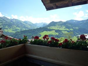 a balcony with red flowers and a view of mountains at Apartment Ferienhaus Niesen View by Interhome in Erlenbach im Simmental
