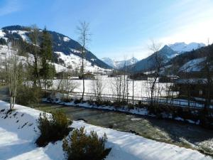 a snow covered field with a fence and mountains at Apartment La Sarine 212 by Interhome in Gstaad