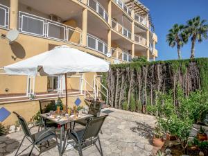 a table with an umbrella and chairs in front of a building at Apartment El Datiler by Interhome in Denia