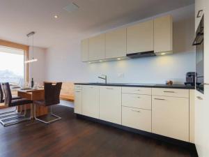 a kitchen with white cabinets and a table with chairs at Apartment Apartmenthaus Riederhoru A 1- OG Ost by Interhome in Riederalp