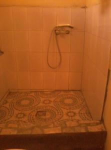 a white tiled bathroom with a shower with a tile floor at Chez Zizou Manakara in Manakara